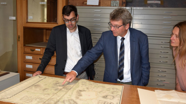 Das Foto zeigt die Personen beim Betrachten einer historischen Landkarte